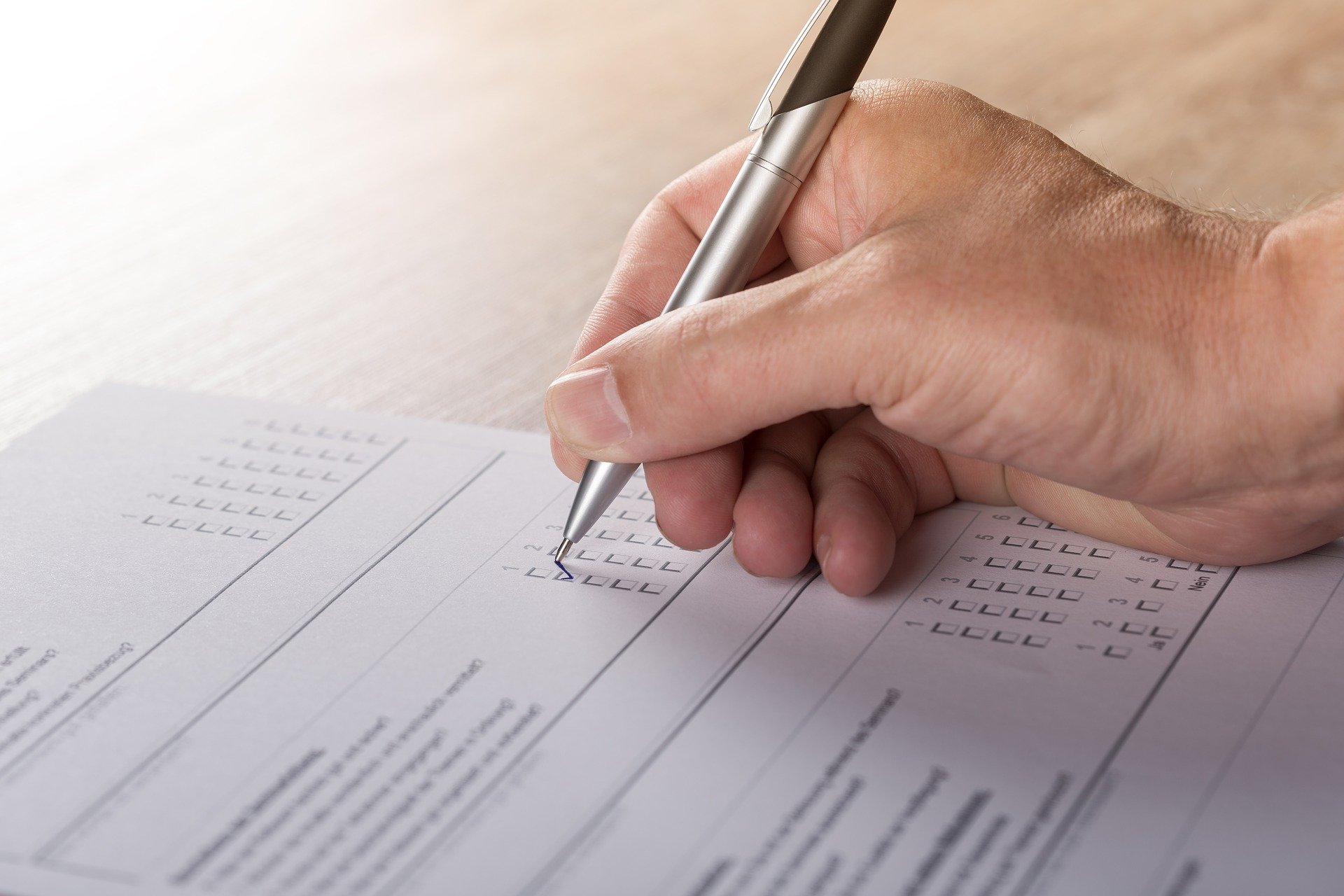 a hand is filling out a survey with a pen